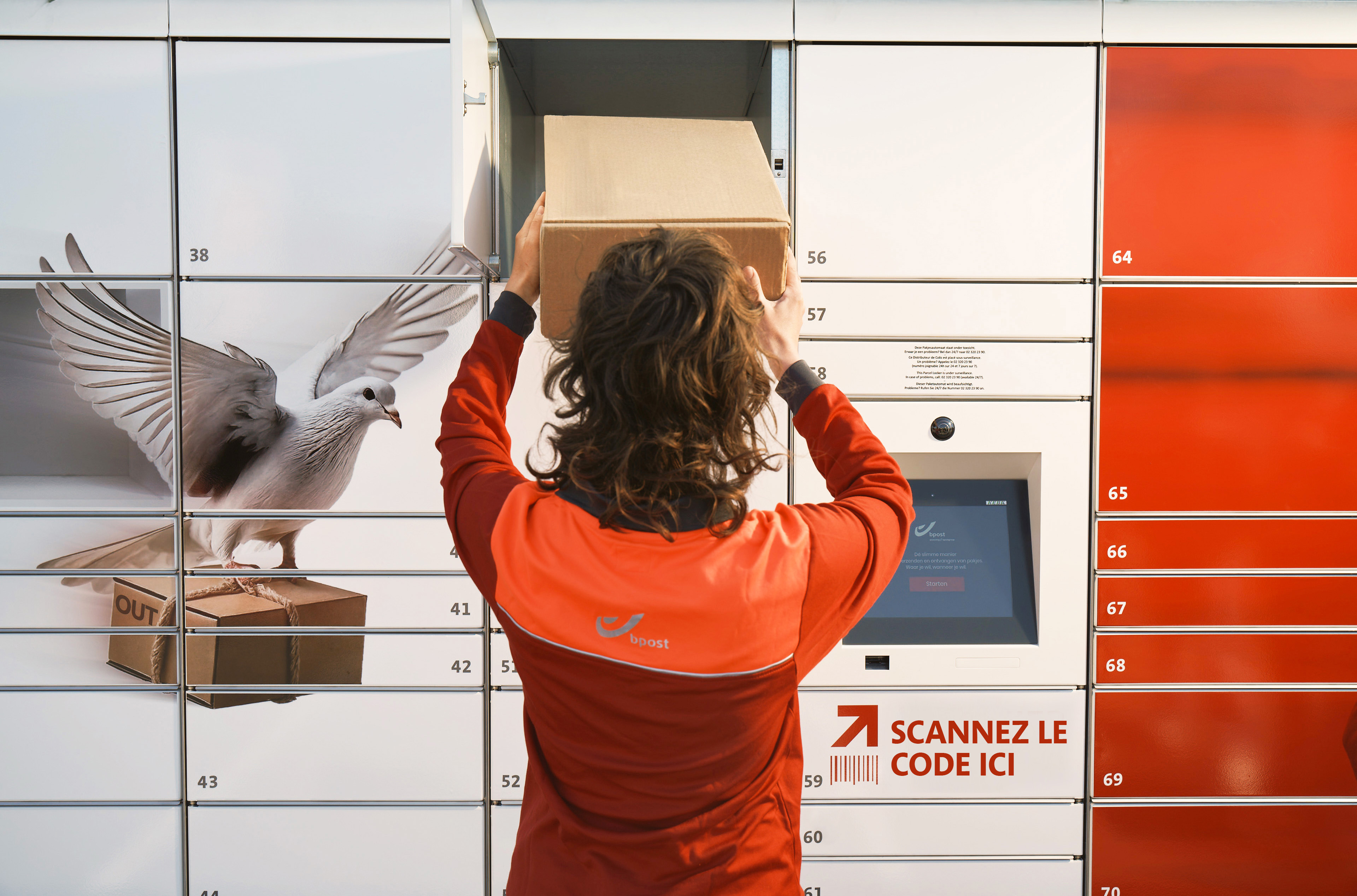 A bpost employee placing a parcel in a bbox parcel locker