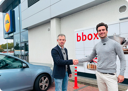 2 personnes se serrent la main devant un distributeur bbox auprès d'une succursale Lidl