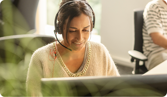 A person with a headset behind a computer screen